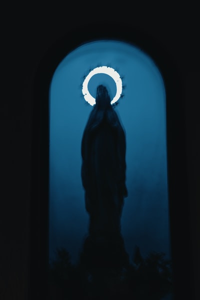 The silhouette of a man standing in front of a blue

